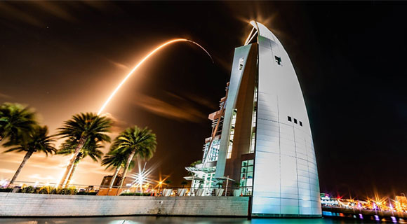 A launch arcs over Port Canaveral at night